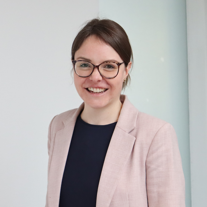 Ein Porträt der Professorin Dr. Eva Jakob. Sie trägt einen hellen Blazer, darunter ein dunkelblaues T-Shirt und eine runde Brille. Freundlich und offen lächelt sie in die Kamera.